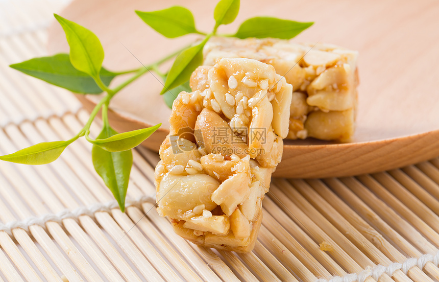 一块芝麻花生酥放在小木盘子上面图片