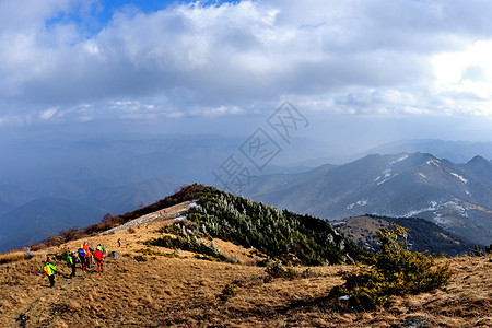 冻山峻峭山峰之上白云飘飘、远眺山梁如巨龙蜿蜒线路员高清图片