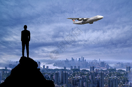 商务人士站在山顶仰望飞过的飞机图片