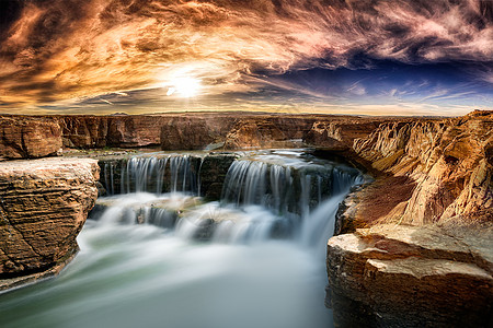 美国风景阳光下岩石边的瀑布背景