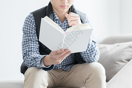 坐在沙发上的男人坐在沙发上看书的年轻人背景