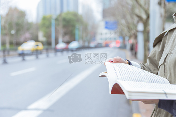 公交亭边等车边看书的女生图片