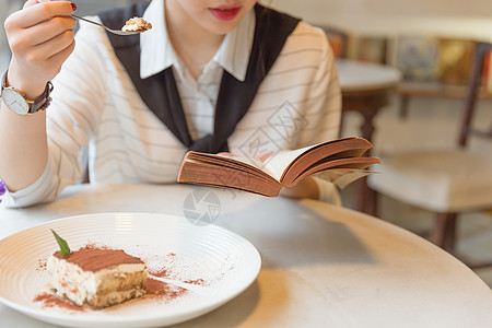 咖啡馆内女孩边吃甜品边看书图片