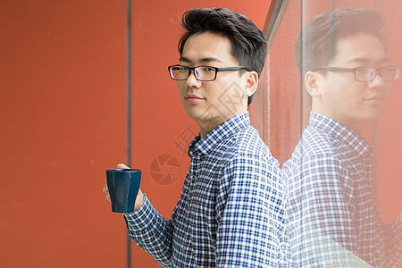 办公室落地窗喝茶的年轻人图片