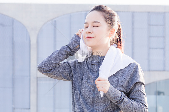 女性夕阳下跑步运动休息擦汗图片