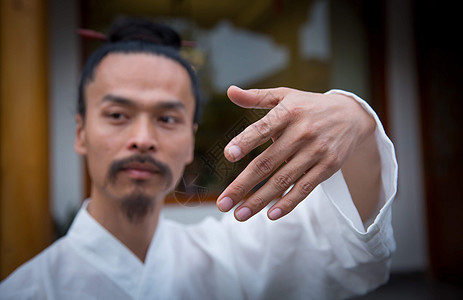 一位白衣道士在院子里练习武术的手部面部特写背景图片