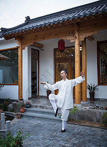 一位道士在古老的房屋前练习武术背景图片
