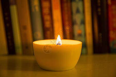 彩色书一杯燃烧的蜡烛放在书桌旁背景