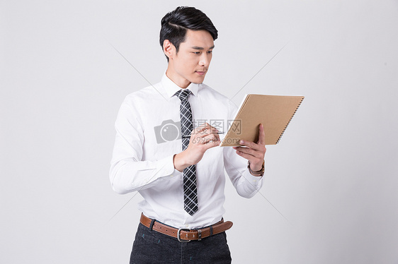 商务男士拿着笔和纸看向远方图片