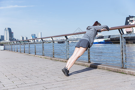 运动女孩阳光下扶栏杆压腿背景图片