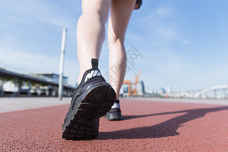 阳光下运动女孩跑道上走路背景图片