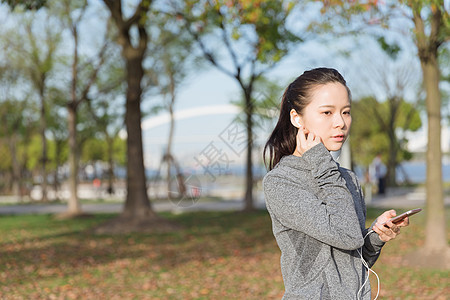 公园运动女孩阳光下休息听音乐图片