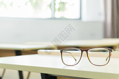 教室里书桌上的眼镜特写背景图片