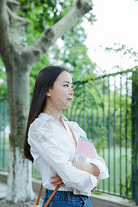 女大学生抱书图绿树下清新女大学生抱书形象背景