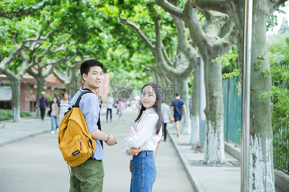 青春男女学生走在校园路上回头图片