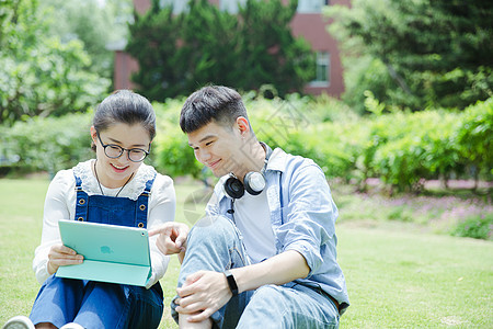 阳光下男女大学生在看平板电脑图片