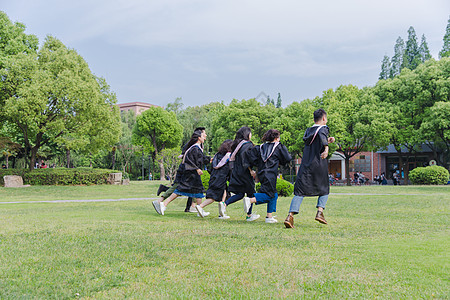 大学建筑毕业季穿学士服的学生在奔跑背景
