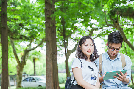 文静男女大学生坐着看平板电脑高清图片