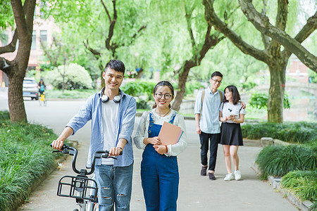 青春大学生推自行车散步聊天图片