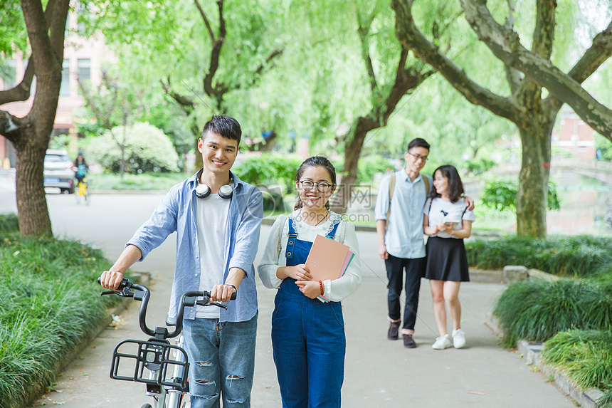 青春大学生推自行车散步聊天图片