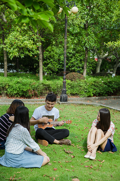 大学生男女草地休息听弹奏图片