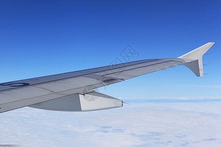 飞行在蓝天中的客机机翼背景图片