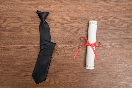 毕业证书与黑色领带组合平铺背景图片