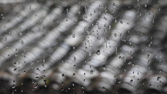 雨水玻璃窗带雨滴的玻璃窗及窗外屋顶背景