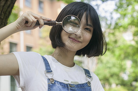 学校绿荫女学生玩放大镜高清图片