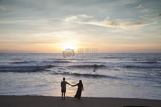 情侣在夕阳西下的海边看大海图片