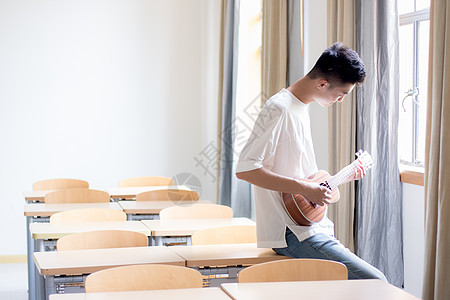 校园吉他教室里弹尤克里里的男同学背景