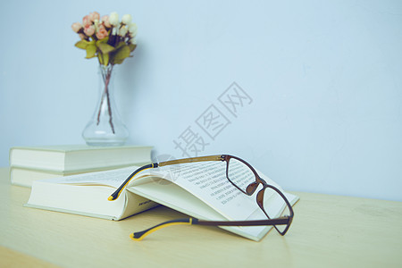书桌上的书、花瓶和眼镜背景图片
