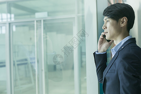 商务男士在机场大厅落地玻璃前用电话通讯图片