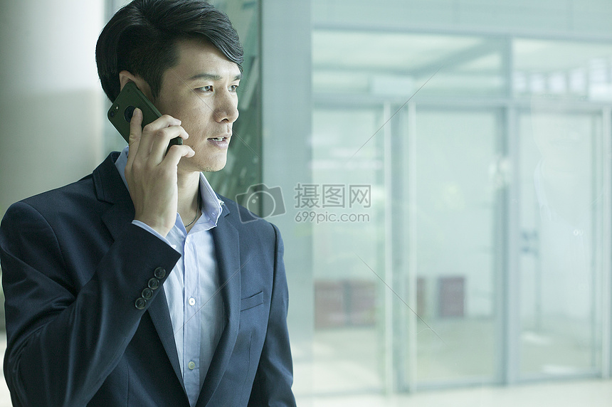 商务男士在机场大厅落地玻璃前用电话通讯图片