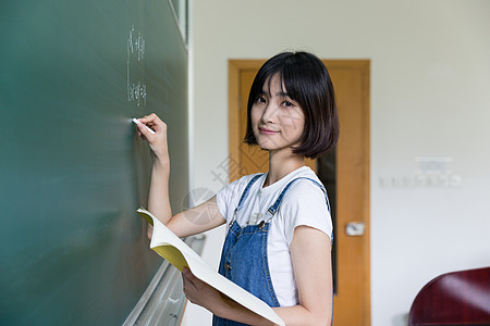 正在教室黑板写板书的女生图片