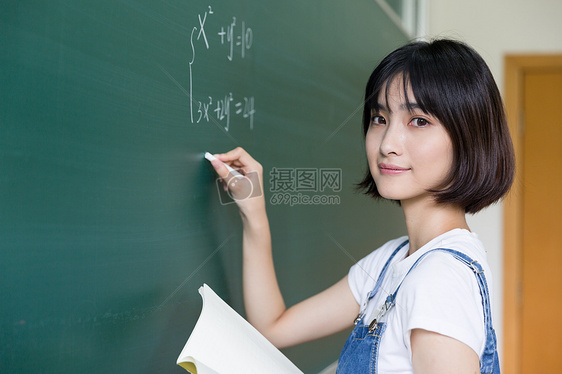 正在教室黑板写板书的女生图片