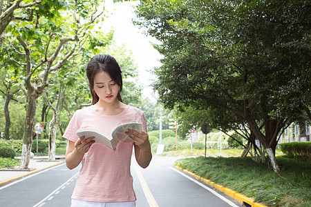 拿着书站在校园林荫道上的高中生图片