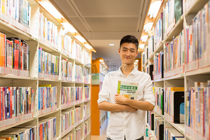 站在图书馆书架旁看书的帅气男同学图片