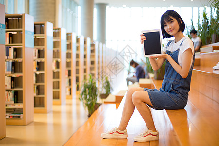 图书馆座位坐在图书馆使用平板的女生背景