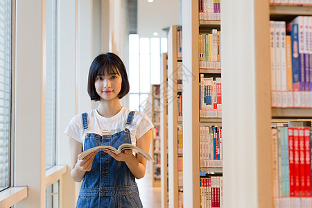 少年读书图书馆里站着看书的女生背景