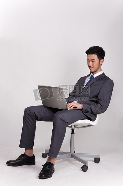 坐着操作笔记本电脑的商务人士图片