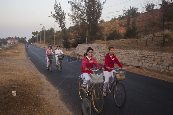 女学生们微笑骑车在上学路上图片