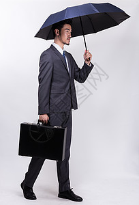 走路看手机提着公文包撑伞走路的商务人士背景
