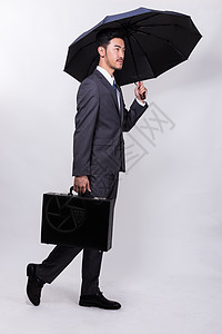 提着公文包撑伞走路的商务人士背景