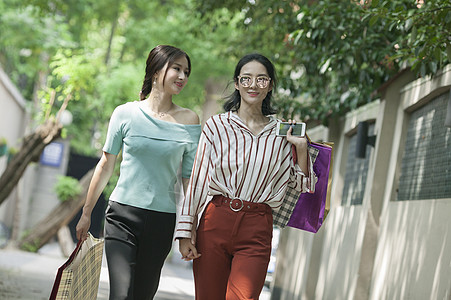 女性闺蜜在小路上逛街购物背景图片