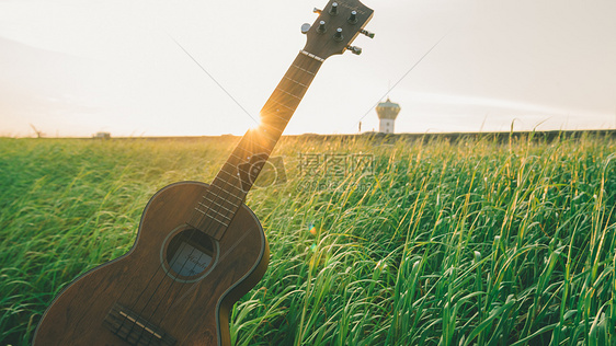 夕阳下的草原和吉他图片
