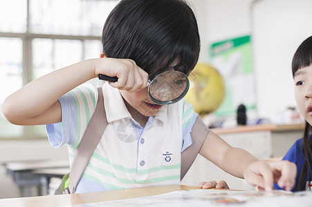 女同学在教室用放大镜研究图片