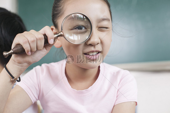 女同学在教室用放大镜研究图片