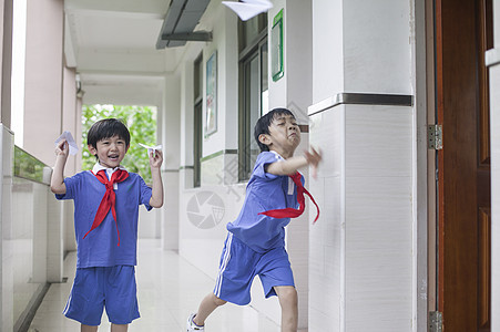 男学生在学校里折飞机玩耍图片