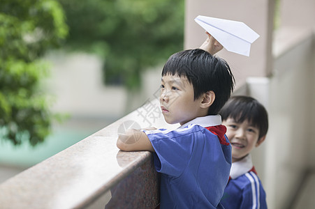 男学生在学校里折飞机玩耍图片